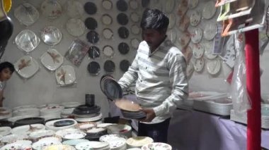 Hintli adam yerel pazarda çeşitli tabaklar satıyor.