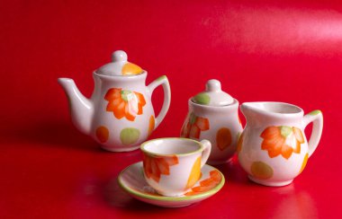 Kırmızı arkaplanda çaydanlık bulunan seramik bardaklar