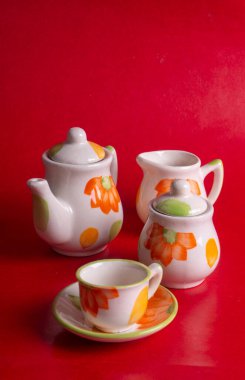 Kırmızı arkaplanda çaydanlık bulunan seramik bardaklar