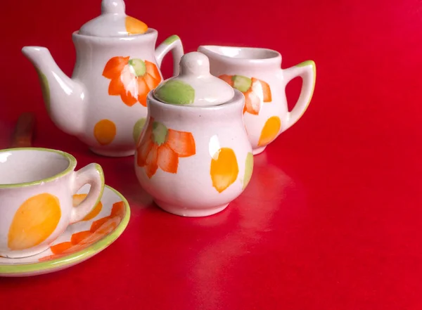 stock image ceramic cups with kettle on red colored background