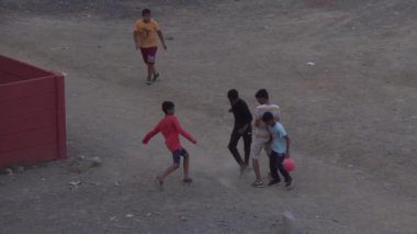Çocuklar dışarıda futbol oynuyor.