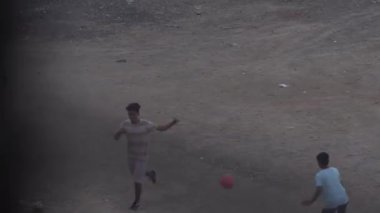 Çocuklar dışarıda futbol oynuyor.