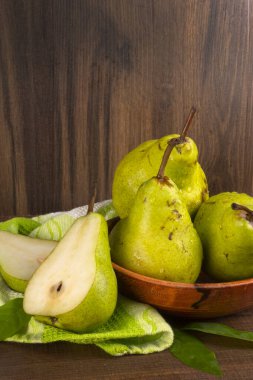 Tahta bir masanın üzerinde tekstil peçetesi olan taze armutlar.
