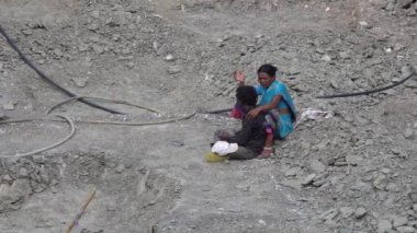 Erkek ve kadın işçiler rahatlar ve inşaat alanında yerde oturur.