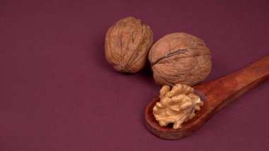Ahşap kaşık, mor arka planda ceviz.