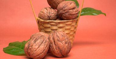 Turuncu arka planda sepetin içinde ceviz yığını