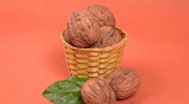 Turuncu arka planda sepetin içinde ceviz yığını