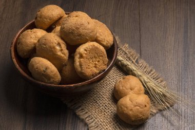 Tahta arka planda buğday ve çuval bezli ev yapımı kurabiyeler.