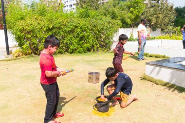 Pune Maharashtra, Hindistan - 18 Mart 2022: Holi festivali sırasında renkli boyalarla oynayan Hintli çocuklar.