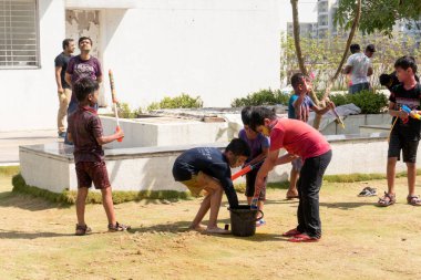 Pune Maharashtra, Hindistan - 18 Mart 2022: Holi festivali sırasında renkli boyalarla oynayan Hintli çocuklar.