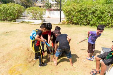Pune Maharashtra, Hindistan - 18 Mart 2022: Holi festivali sırasında renkli boyalarla oynayan Hintli çocuklar.