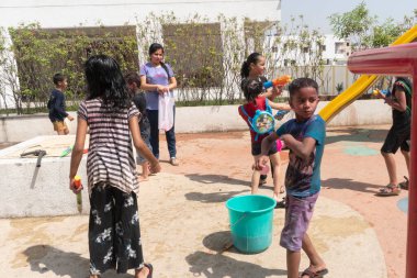 Pune Maharashtra, Hindistan - 18 Mart 2022: Holi festivali sırasında renkli boyalarla oynayan Hintli çocuklar.