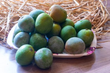 Olgunlaşmamış mango meyvelerini plastik tabakta kapatın.