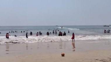 İnsanlar güneşli bir günde Hindistan 'da denizde eğleniyorlar. 
