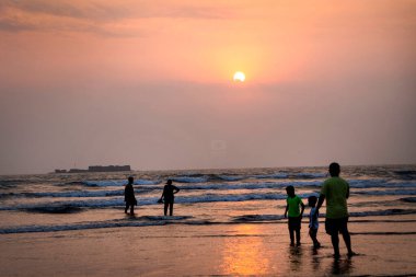 Gün batımında kumsalda turist siluetleri 