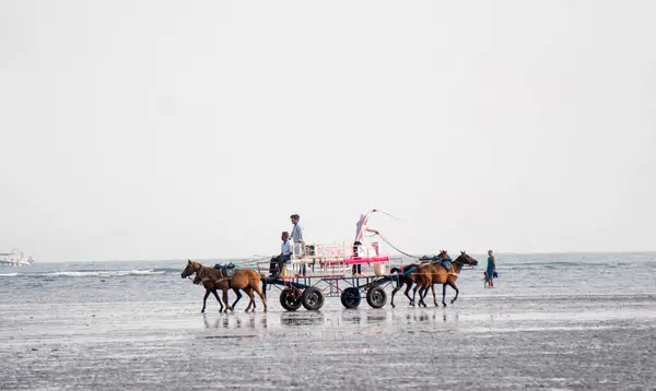 stock image ALIBAG, MAHARASHTRA, INDIA -  25 March 2024 : Unidentified tourists riding a two-wheeled carriage at Alibag beach near Kolaba Fort in morning.