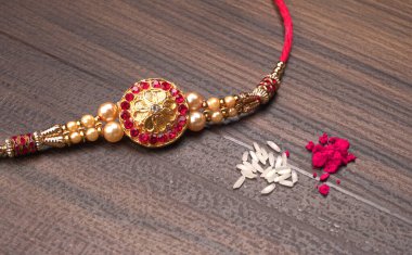 Geleneksel Hint bileziği Rakhi, ahşap zemin üzerinde biraz pirinç ve kırmızı baharat, Kardeş Bağları Raksha bandosu üzerinde bilek