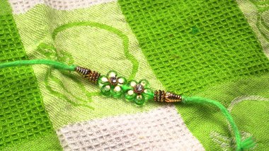 Geleneksel Hint bilekliği Rakhi yeşil örtülü arka planda, Kardeş Bağları Kardeşler Bileğinde Raksha bandhan
