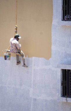 Endüstriyel dağcı duvarları boyarken ipte sallanıyor 