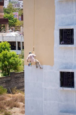 Endüstriyel dağcı duvarları boyarken ipte sallanıyor 