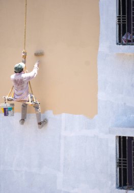 Endüstriyel dağcı duvarları boyarken ipte sallanıyor 