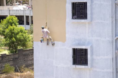 Endüstriyel dağcı duvarları boyarken ipte sallanıyor 