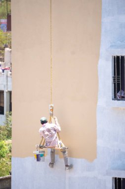 Endüstriyel dağcı duvarları boyarken ipte sallanıyor 