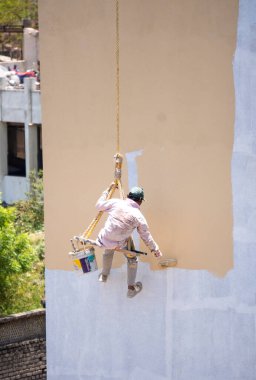 Endüstriyel dağcı duvarları boyarken ipte sallanıyor 