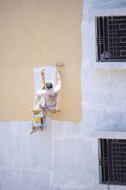 Endüstriyel dağcı duvarları boyarken ipte sallanıyor 