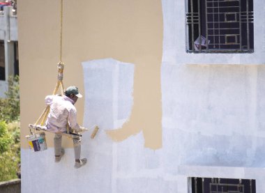 Endüstriyel dağcı duvarları boyarken ipte sallanıyor 