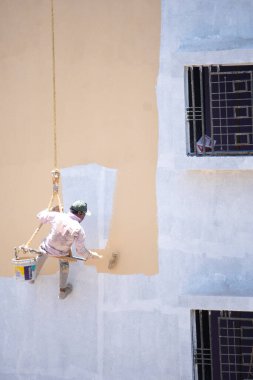 Endüstriyel dağcı duvarları boyarken ipte sallanıyor 