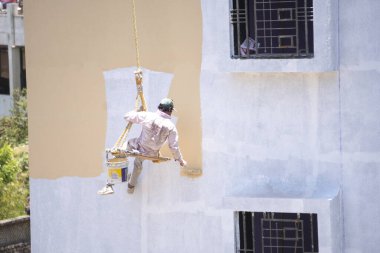 Endüstriyel dağcı duvarları boyarken ipte sallanıyor 