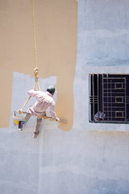 Endüstriyel dağcı duvarları boyarken ipte sallanıyor 