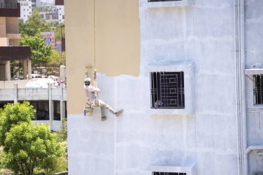 Endüstriyel dağcı duvarları boyarken ipte sallanıyor 