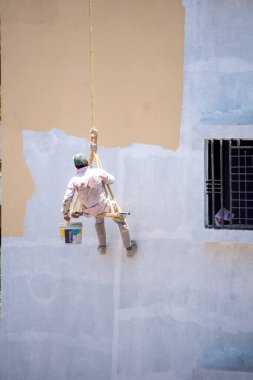 Endüstriyel dağcı duvarları boyarken ipte sallanıyor 