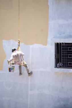 Endüstriyel dağcı duvarları boyarken ipte sallanıyor 