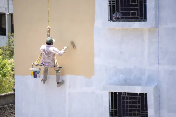 Endüstriyel dağcı duvarları boyarken ipte sallanıyor 