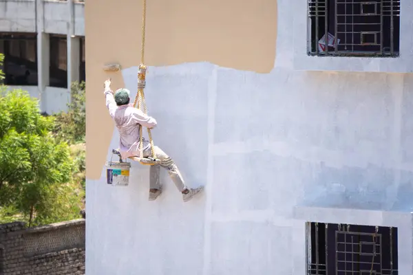 Endüstriyel dağcı duvarları boyarken ipte sallanıyor 