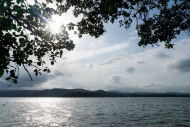 Dağlardaki gölün güzel manzarası, yeşil ağaçlar ve bulutlu gökyüzü. 