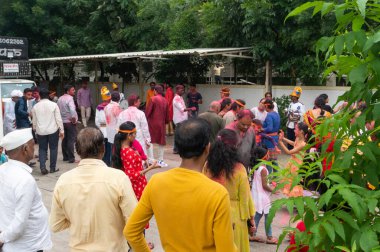 PUNE, MAHARASHTRA, INDIA - 8 EYLÜL 2022: Kimliği belirlenemeyen inançlı insanlar, su kaynaklarının yakınına dalmadan önce Hindu tanrısı Ganesha 'ya dua ediyorlar (Ganesh Chaturthi), yıllık festival