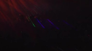 Konserde neon ışıkların ve dans eden insanların gece görüşü