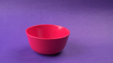 Mor zemin üzerinde kırmızı boş seramik kasenin yakın plan görüntüsü.                   