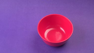 Mor zemin üzerinde kırmızı boş seramik kasenin yakın plan görüntüsü.                   