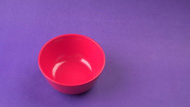 Mor zemin üzerinde kırmızı boş seramik kasenin yakın plan görüntüsü.                   