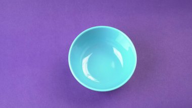 Mor zemin üzerinde mavi boş seramik kasenin yakın plan görüntüsü.                   