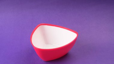 Mor zemin üzerinde kırmızı boş seramik kasenin yakın plan görüntüsü.                   