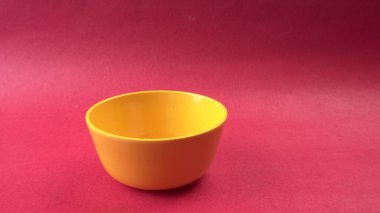 Kırmızı zemin üzerindeki boş sarı kasenin yakın plan görüntüsü       