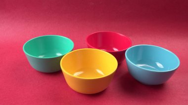 Kırmızı arkaplanda renkli boş kaselerin yakın plan görüntüsü                    