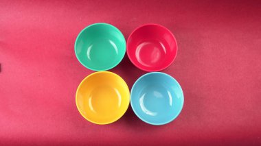 Kırmızı arkaplanda renkli boş kaselerin yakın plan görüntüsü                    