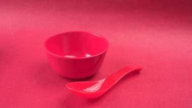 Kırmızı arka planda kaşıkla kırmızı boş kasenin yakın plan görüntüsü                  